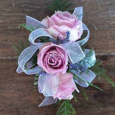 Pink roses with lavender ribbon and greenery on a wooden surface