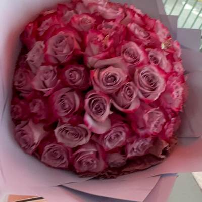Round bouquet of pink roses wrapped in pale paper