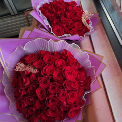Two bouquets of red roses wrapped in purple paper