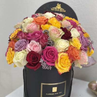 Round box arrangement of multicolored roses in a black hatbox