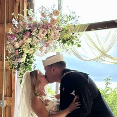 Bride and groom kissing beneath a pastel floral arch