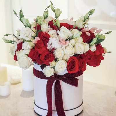 Red and white rose arrangement in a white hat box with a burgundy ribbon