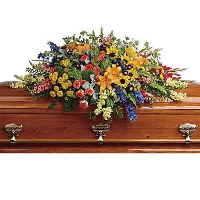 Colorful casket spray with mixed flowers on a wooden coffin