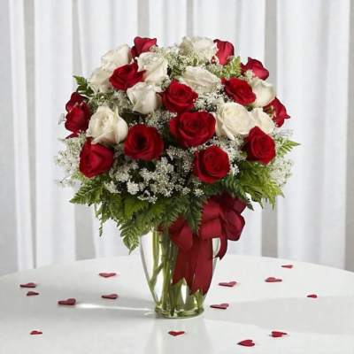 Bouquet of red and white roses in a clear glass vase with a red ribbon