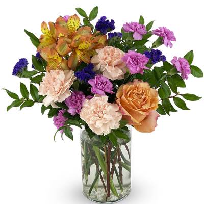 Mixed bouquet of roses, carnations, and alstroemeria in a clear glass vase