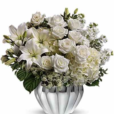 White roses and lilies arranged in a silver vase