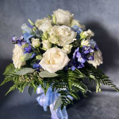 White roses and blue flowers in a hand-tied bouquet with ribbon