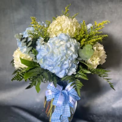 Blue and white hydrangea bouquet in a glass vase with a blue ribbon