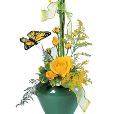Yellow lilies and roses in a green vase with a butterfly accent