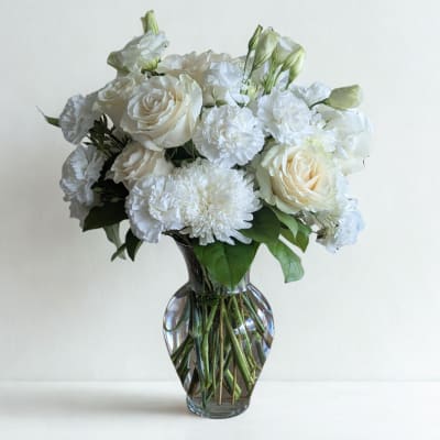 White roses and carnations arranged in a clear glass vase