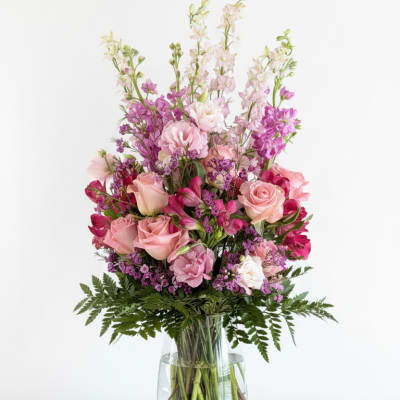 Pink and purple mixed flower arrangement in a clear glass vase
