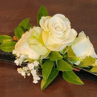 White rose boutonniere with green leaves and a black ribbon