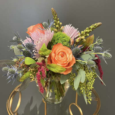 Orange rose and pink blooms in a clear glass vase