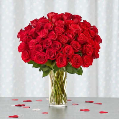 A tall glass vase holds a large bouquet of red roses.