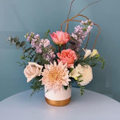 Mixed pastel floral arrangement in a white and gold vase