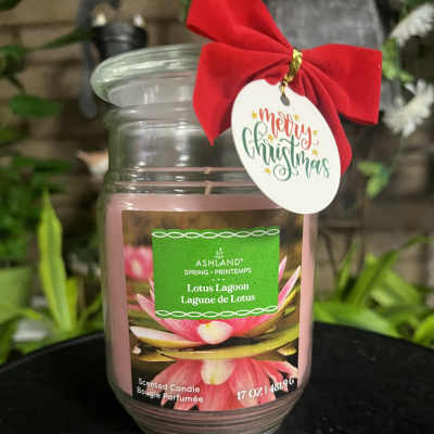 Pink scented candle in a glass jar with a red bow and Merry Christmas tag