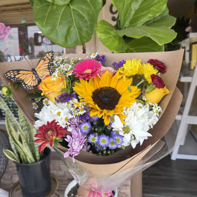 Colorful mixed bouquet with a sunflower and roses, wrapped in brown paper