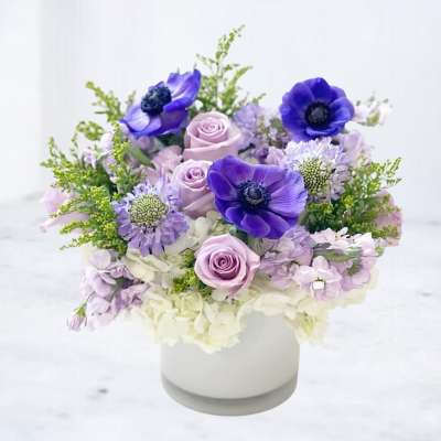 Lavender and purple floral arrangement in a white vase