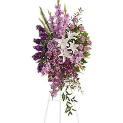 Tall lavender and purple standing spray with white lilies on a white easel stand