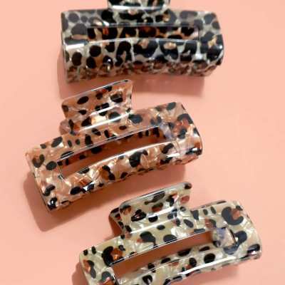 Three leopard-print hair claw clips on a pink background