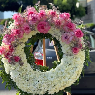 Large pink and white floral wreath on a wooden easel