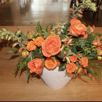 Orange rose arrangement in a white textured vase