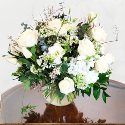 White rose bouquet in a vase with mixed greenery
