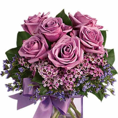 Pink roses in a clear square vase with a purple ribbon