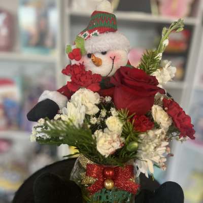 Snowman figurine in a holiday flower arrangement with red and white blooms