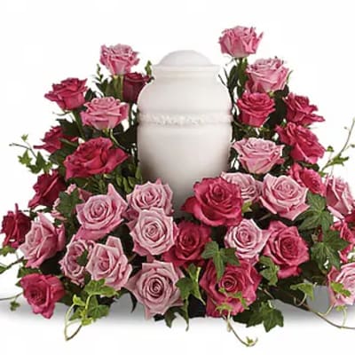 Pink and red roses arranged around a white urn