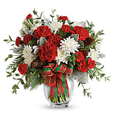 Red and white flowers in a glass vase with a plaid ribbon