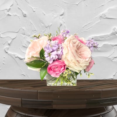 Pink and cream roses with lavender flowers in a glass vase