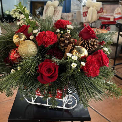Christmas arrangement with red roses, carnations, pinecones, and gold ornaments