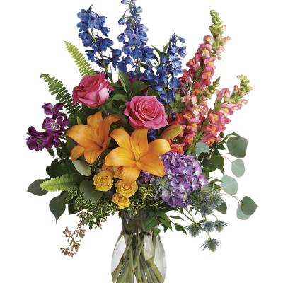 Mixed bouquet with orange lilies, pink roses, and blue delphinium in a glass vase