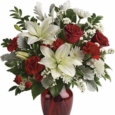 Red and white flower arrangement in a red glass vase