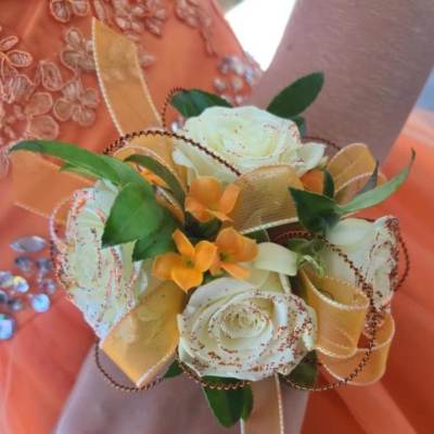 Wrist corsage with white roses and orange flowers on ribbon