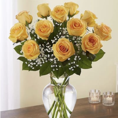 Arrangement of yellow roses with white filler flowers in a clear glass vase