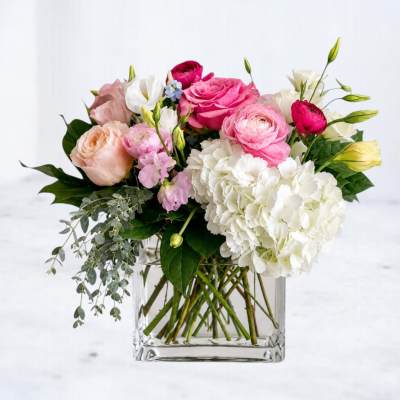 Mixed pink and white flowers arranged in a clear glass vase