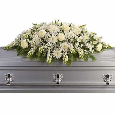 White floral casket spray with green accents on a gray casket