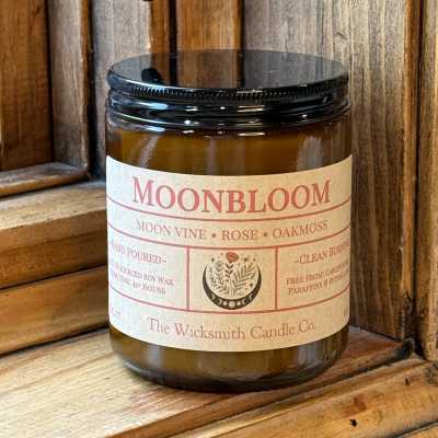Amber candle jar with a black lid and labeled Moonbloom scent