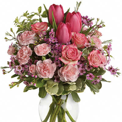 Pink tulips, roses, and carnations with small purple blooms arranged in a clear glass vase