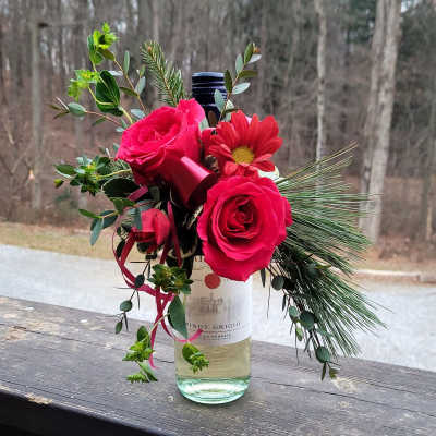 Pink roses and a red daisy in a wine bottle vase