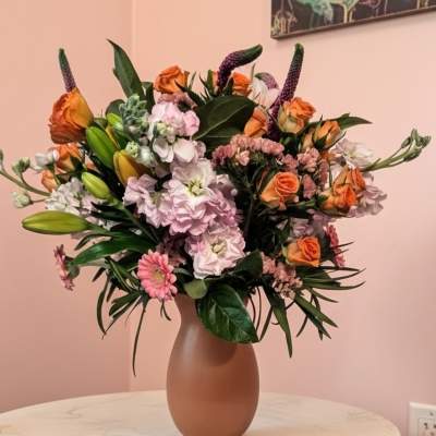 Mixed bouquet of orange and pink flowers in a matte vase