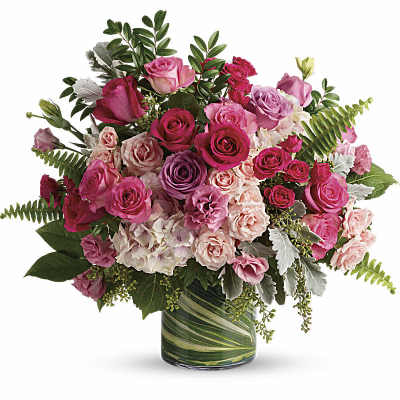 Bouquet of pink and lavender roses with pale hydrangeas in a leaf-lined glass vase