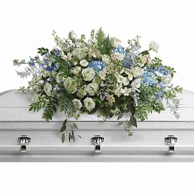 White and blue casket spray of roses and mixed flowers arranged on a white casket