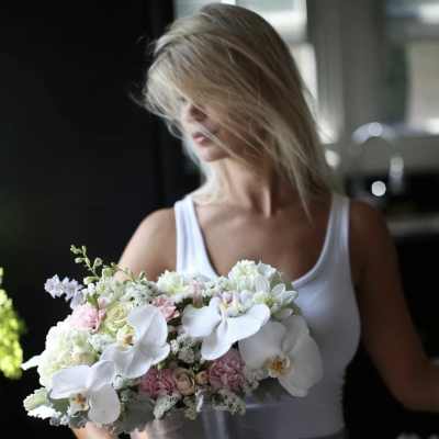 Woman holding a pastel bouquet with white orchids and pink roses