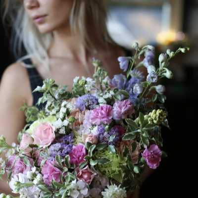 Woman holding a pastel bouquet of pink and purple flowers