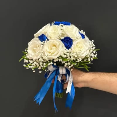 Handheld bouquet of white and blue roses with ribbon