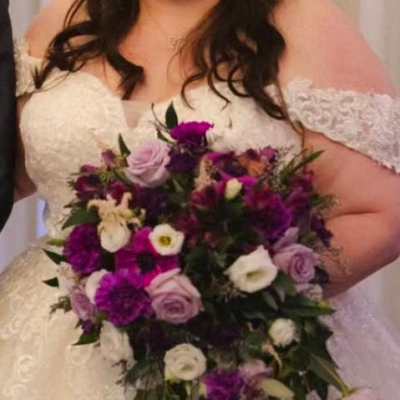 Bride holding a cascading bouquet of purple, lavender, and white flowers