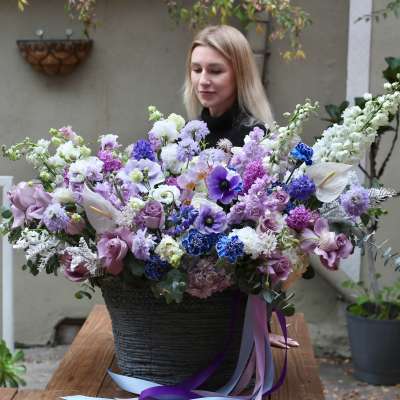 Large lavender and white floral arrangement in a black basket